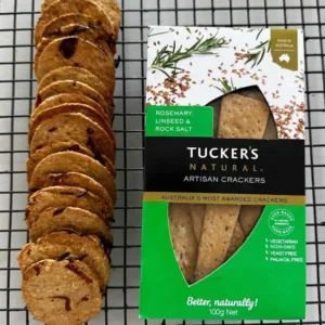 Homemade miso caramelised onion crackers cooling on a wire rack beside a box of Tuckers Natural artisan crackers