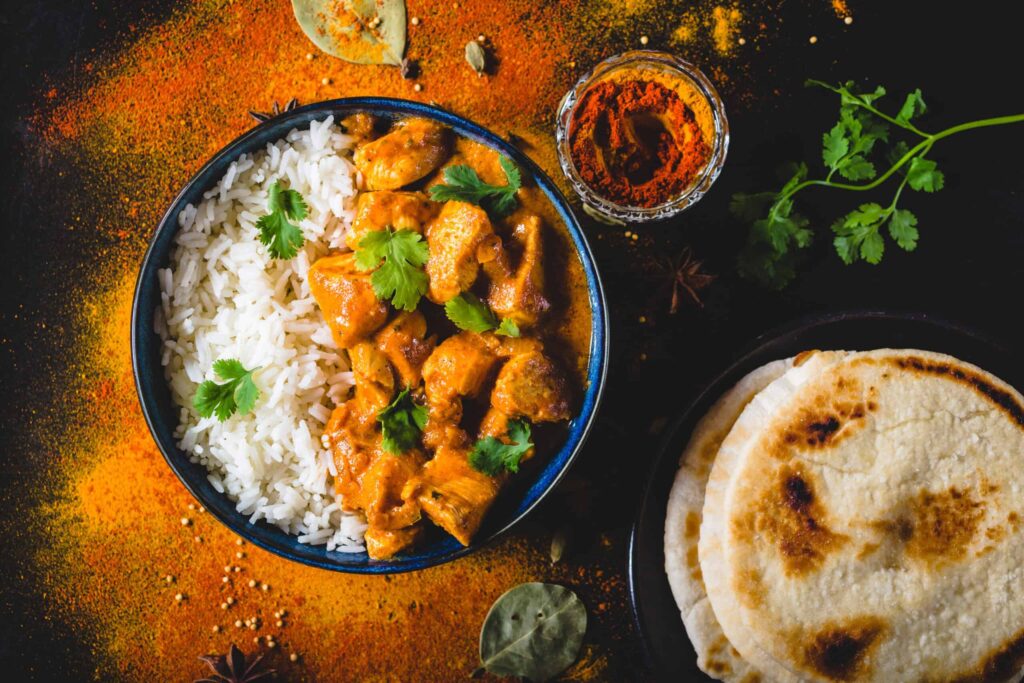 Tandoori spiced chicken in butter sauce served over rice with coriander, naan bread and spices