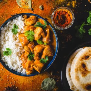 Tandoori spiced chicken in butter sauce served over rice with coriander, naan bread and spices