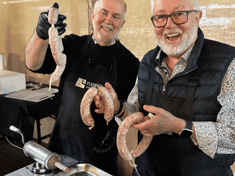 Two presenters holding freshly made sausages in a sausage making class