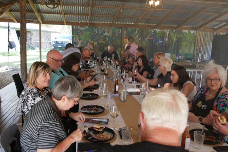 Cooks gathered around a bench rolling fresh pasta together at a Fleurieu cooking class