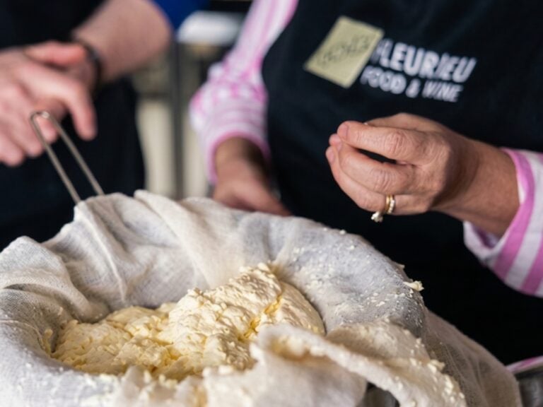 Hands in a Fleurieu Food and Wine apron draining fresh curd through cheesecloth at a cheese-making class