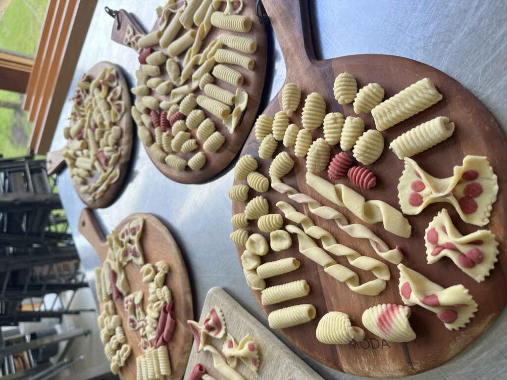Wooden boards covered in freshly made pasta shapes in plain and beetroot dough